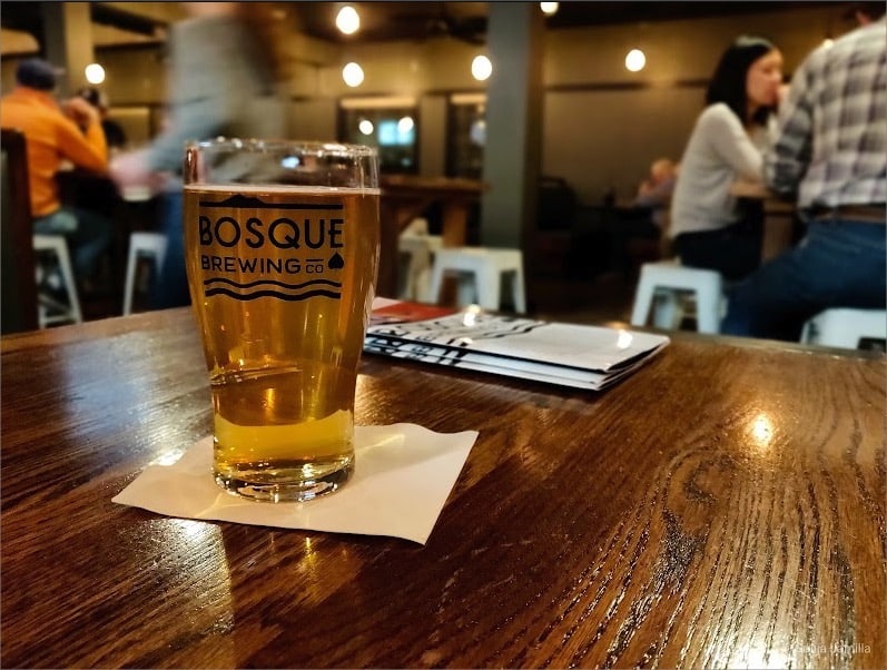 A glass of beer sitting on a wooden table at a brewery in Las Cruces.
