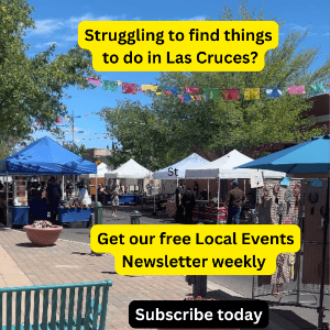 Outdoor market with colorful tents under blue sky, trees around, signs advertising a local events newsletter.